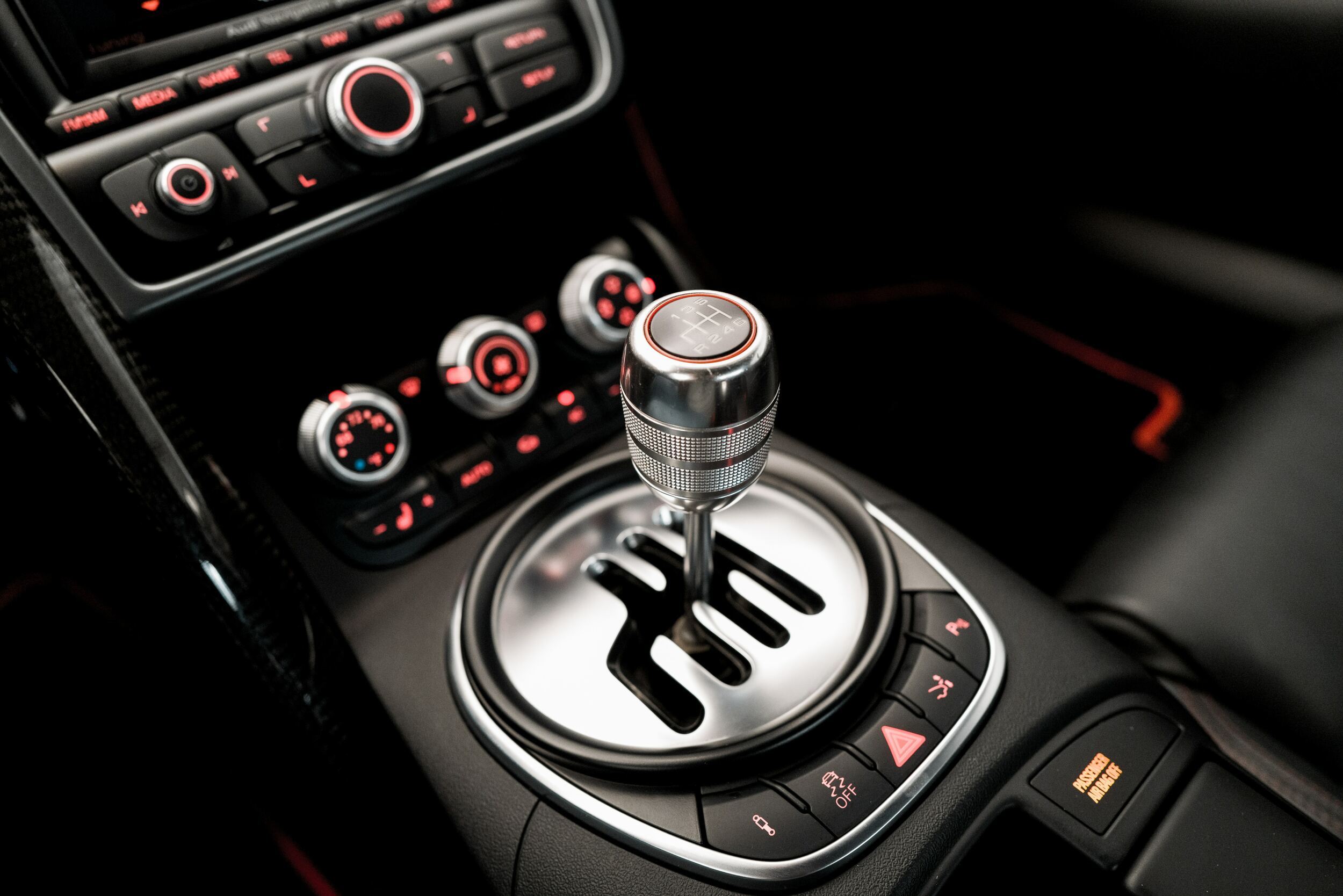 The interior of a car, in black and red. The stick shift forms the centre of the picture