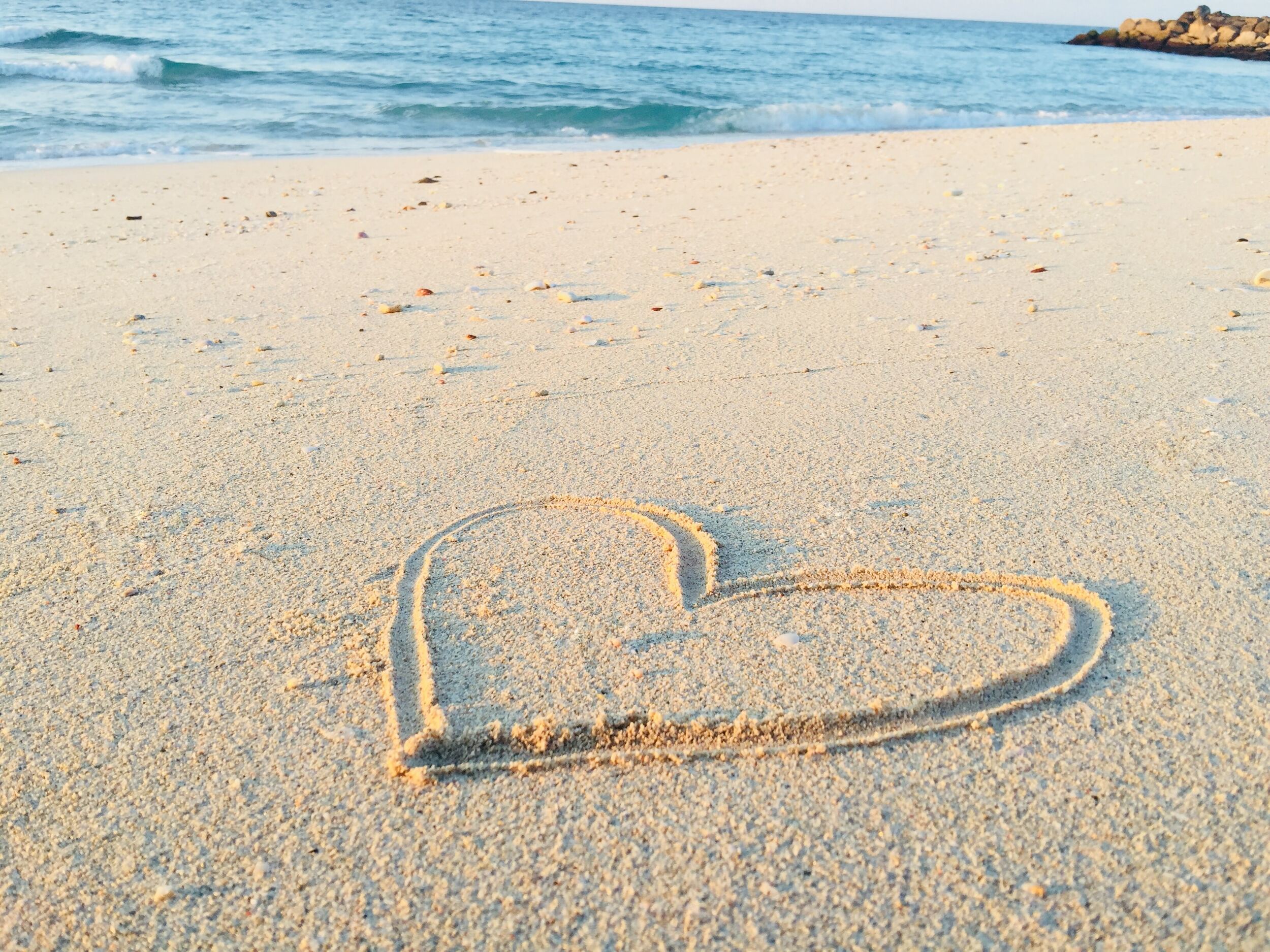 A heart drawn into the sand on a beach.