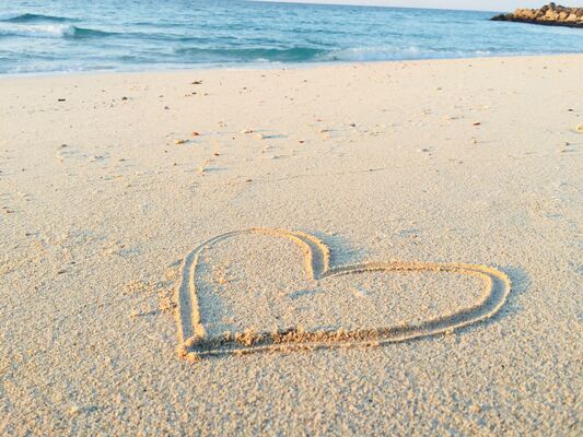 A heart drawn into the sand on a beach.